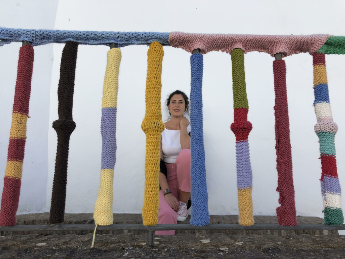 Irene sentada detras de una barandilla forrada de punto de colores