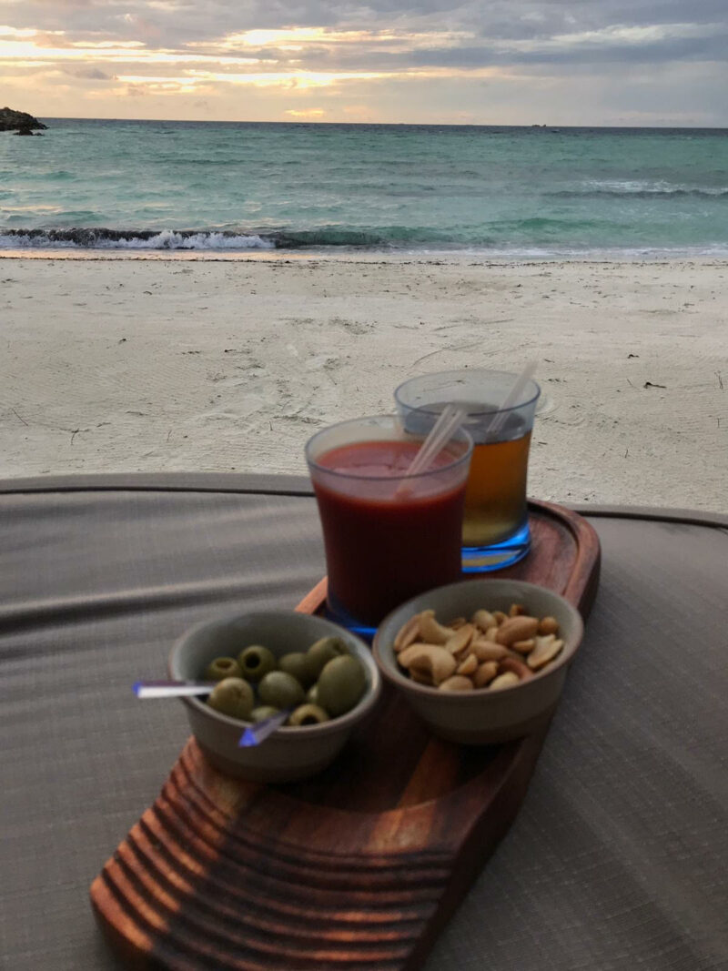 zumo de tomate y cerveza con picoteo con la playa de fondo
