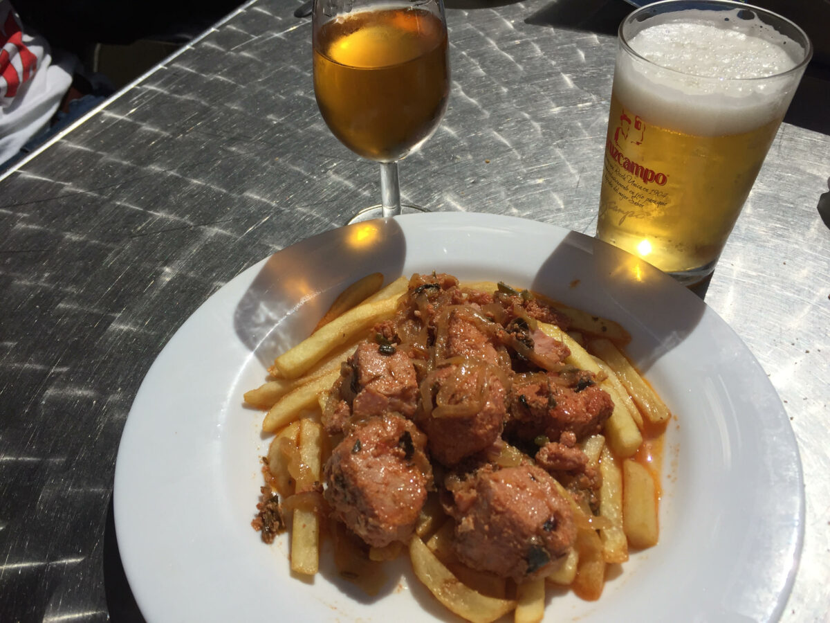 plato de atun encebollado con patatas fritas y cerveza y vino