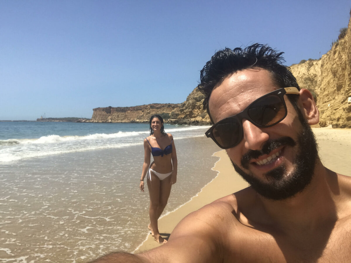 Pareja en la orilla con acantilados de fondo