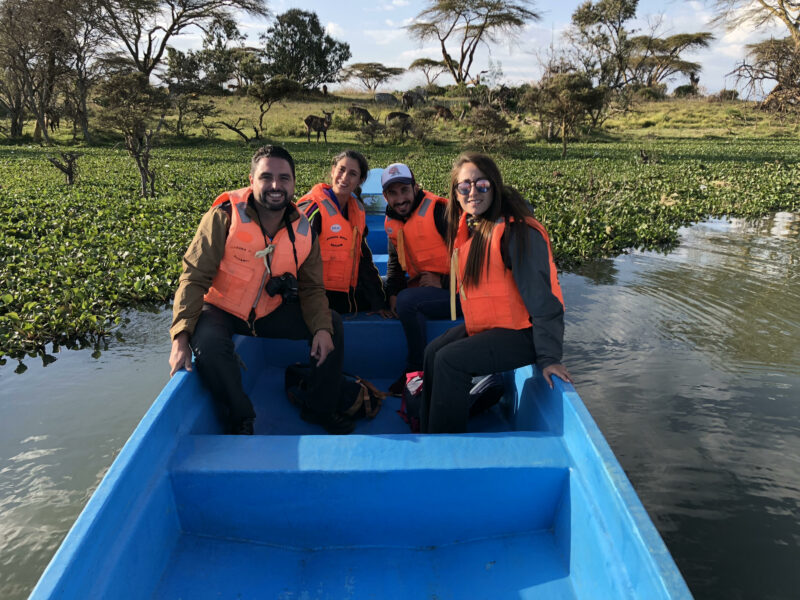 cuatro personas en una barca en el lago Naivasha con animales de fondo