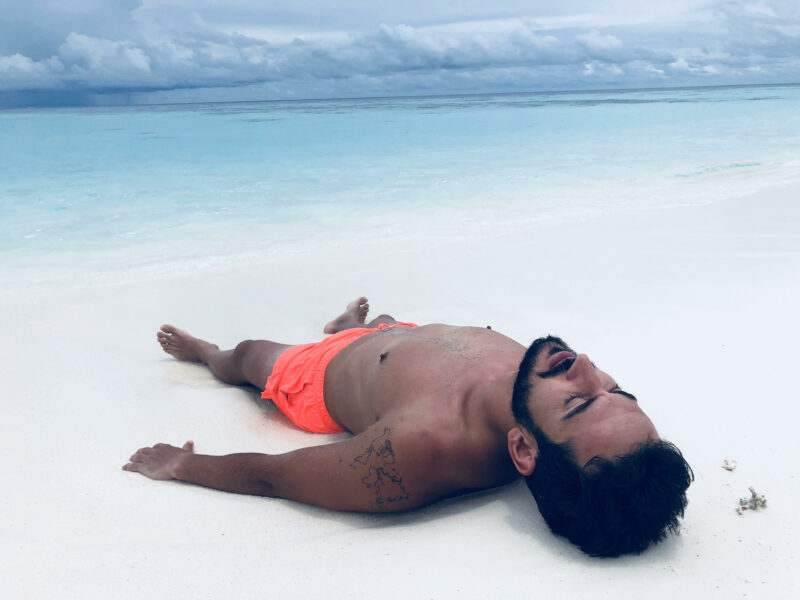 Mnaolo tirado en arena blanca y aguas turquesas de fondo