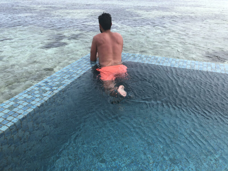 Manolo de espaldas dentro de la piscina privada sobre el mar