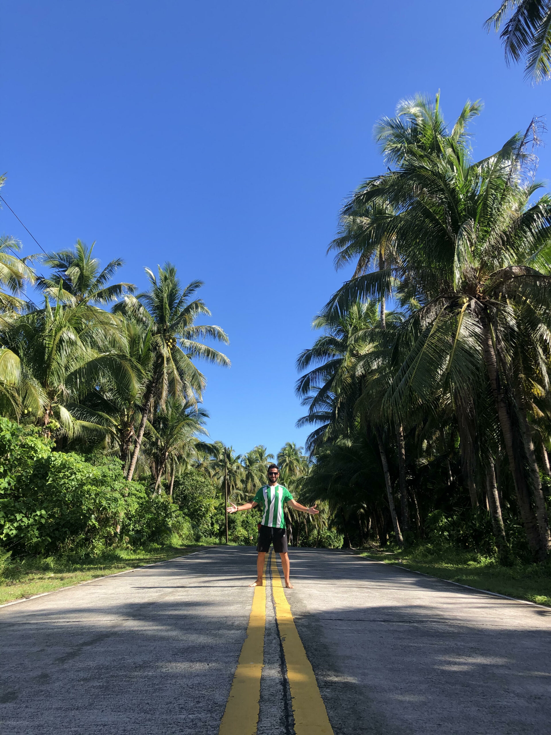 Manolo en medio de la carretera con un palmeral a ambos lados