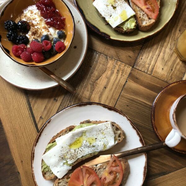 dos tostadas con tomate queso y aguacate y un bowl de fruta