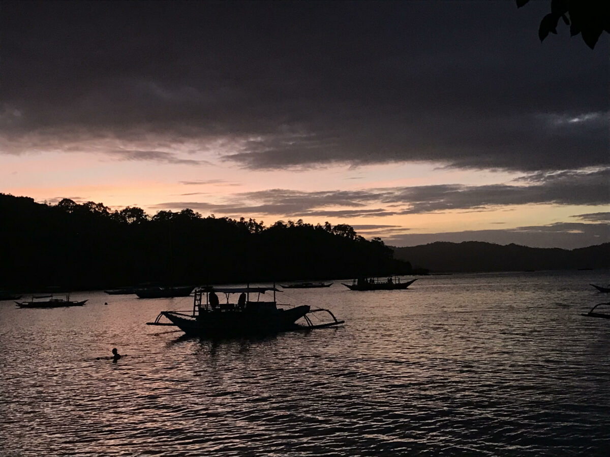 Atardecer con cielo en tonos rosados y barco de pesca típico en Filipinas